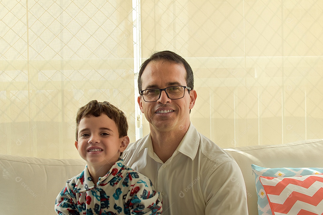 Filho sorridente de 5 anos, sentado no colo do pai 43 anos