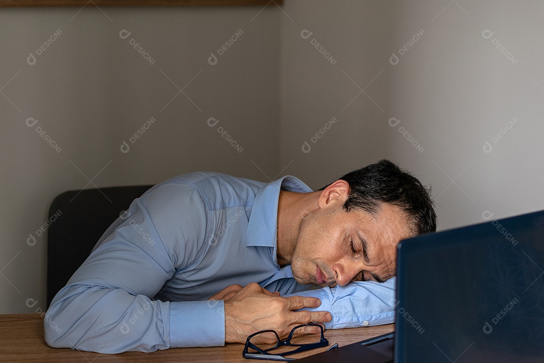 Homem dormindo no trabalho com seu laptop.