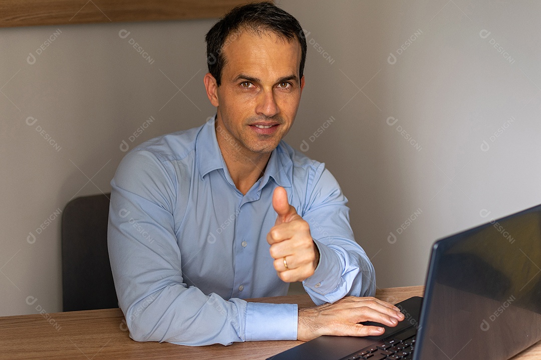 Homem de camisa social azul fazendo sinal de polegar para cima.