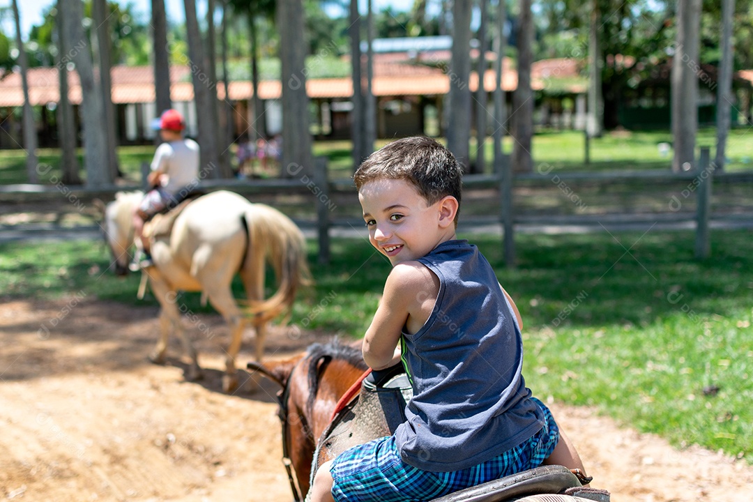 Menino de 5 anos fazendo um passeio a cavalo e olhando para trás.