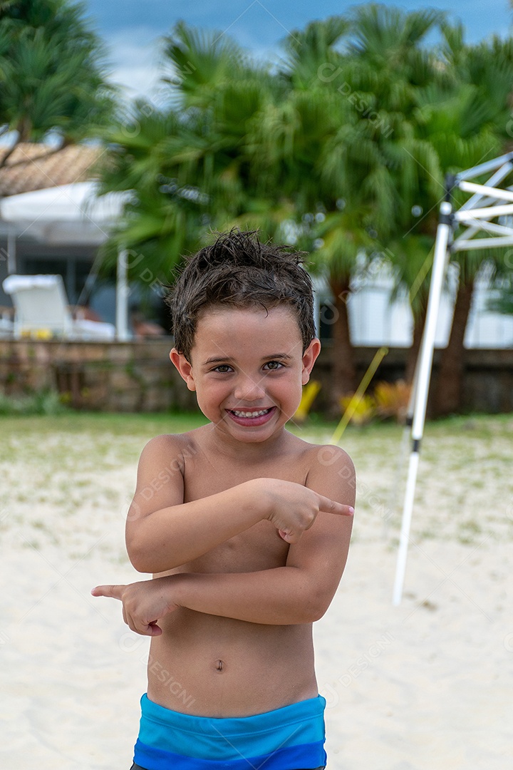 Criança sorrindo na chuva na areia da praia