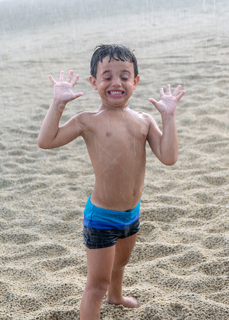 Criança feliz na chuva na areia da praia