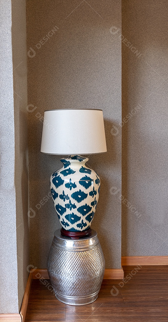 Candeeiro de cabeceira em cima de peça decorativa em metal.