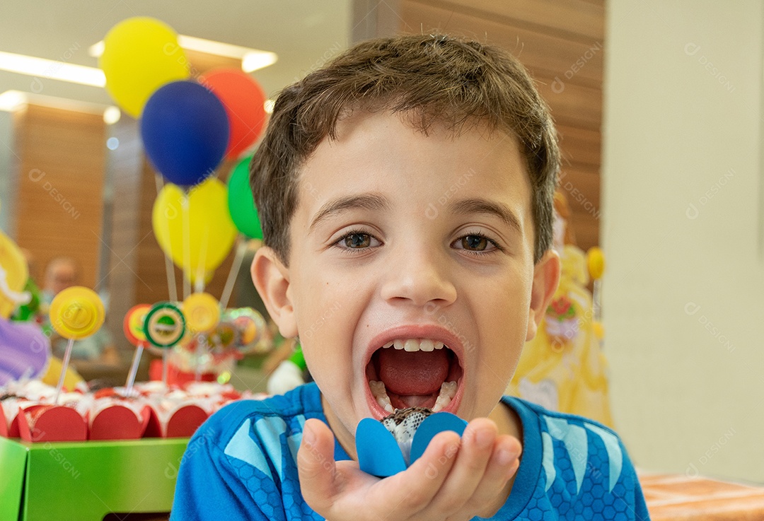 Criança comendo brigadeiro doce.