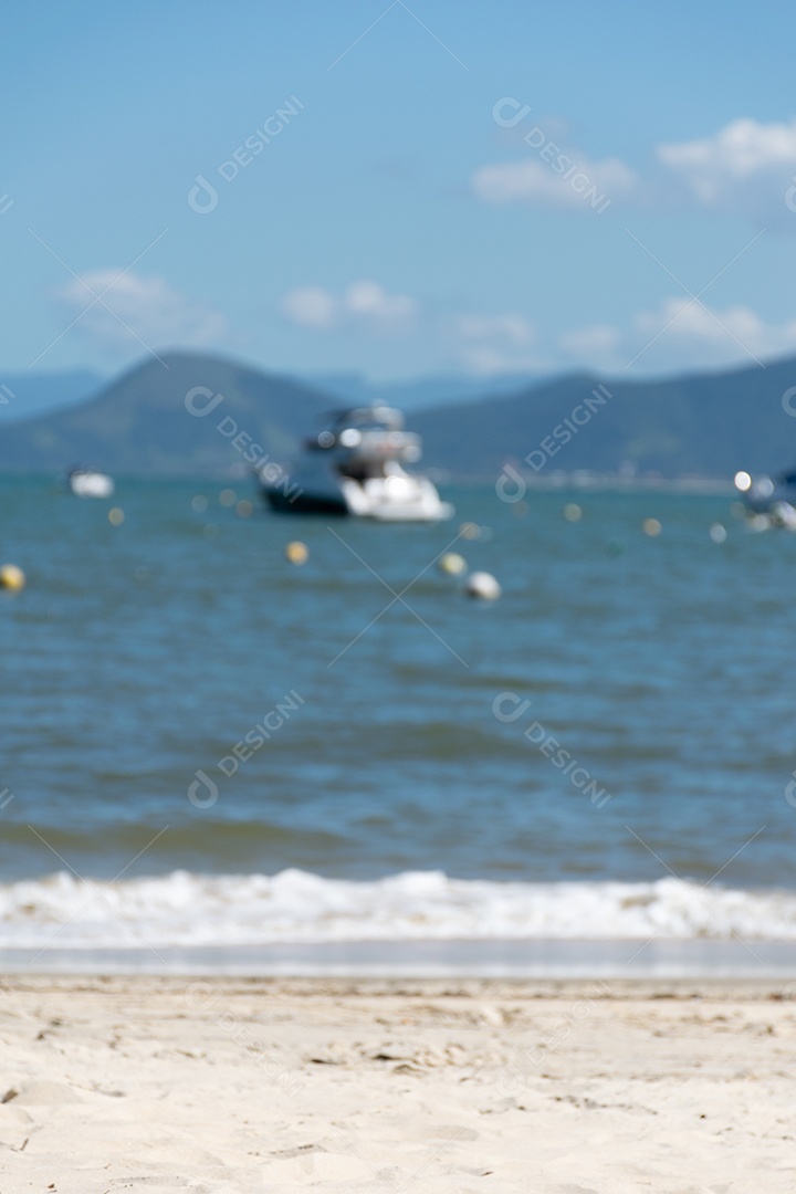 Foto desfocada de areia da praia, mar e barco ao fundo