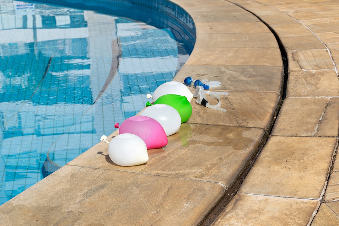 Bombas de água alinhadas na beira da piscina com óculos de natação.