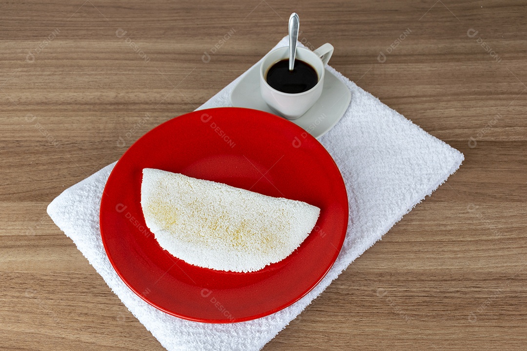 Tapioca com queijo muçarela derretido e café. Em uma mesa de madeira.