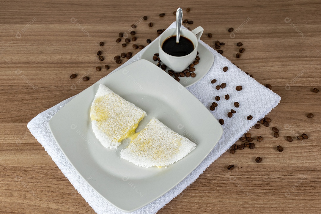 Tapioca com queijo muçarela derretido e café. Em uma mesa de madeira.