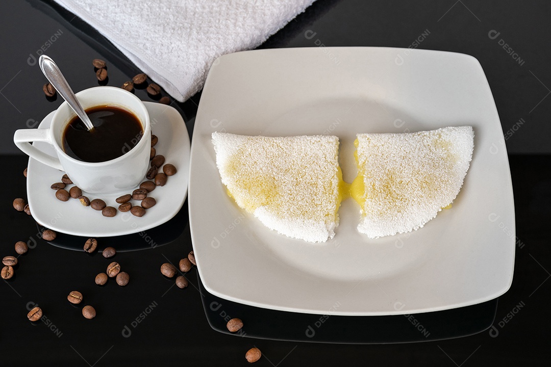 Tapioca com queijo muçarela derretido e café. Em uma mesa de madeira.