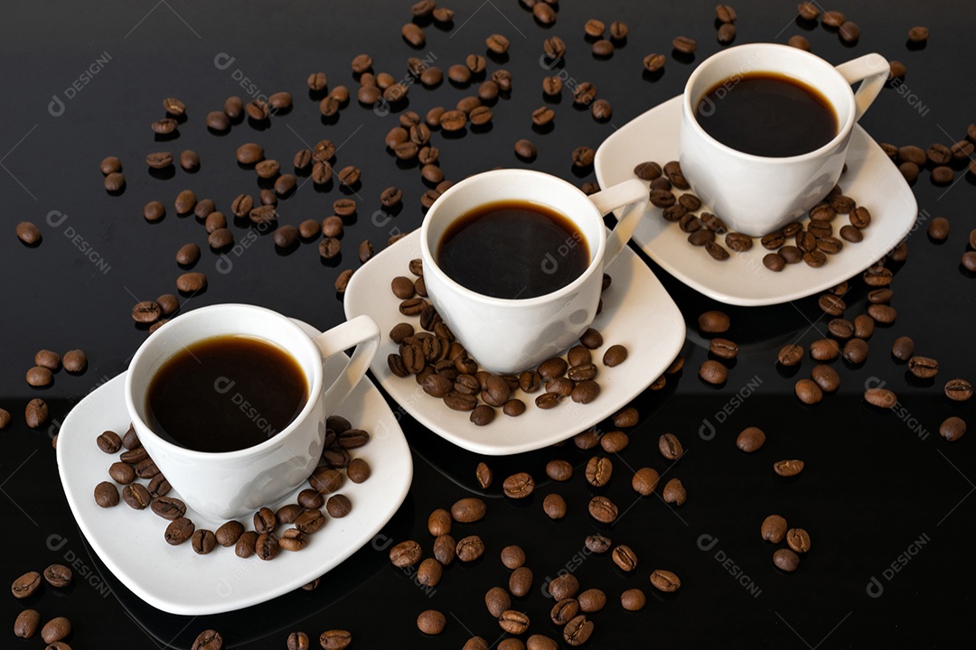 Xícaras e grãos de café no fundo preto espelhado.