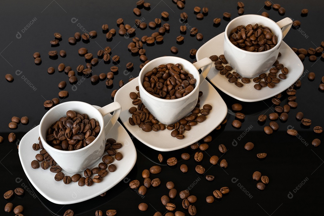 Xícaras e grãos de café no fundo preto espelhado.