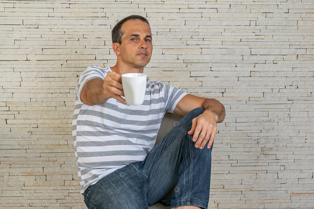 Homem de meia idade sentado na cadeira segurando uma xicara de café