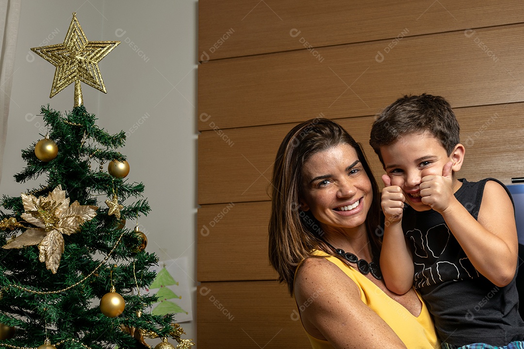 Mãe e filho sorridentes ao lado da árvore de Natal (photo 2).