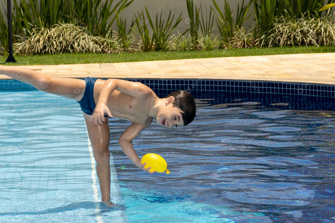 Menino de 6 anos brincando com balão dágua em piscina.