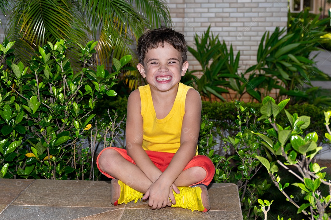 Criança de 6 anos sentada e com um grande sorriso.
