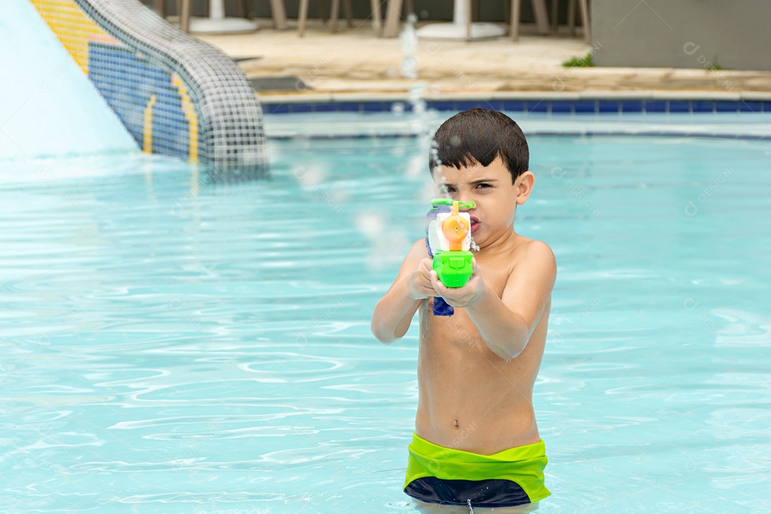 Menino de 6 anos disparando sua pistola de água contra a câmera.