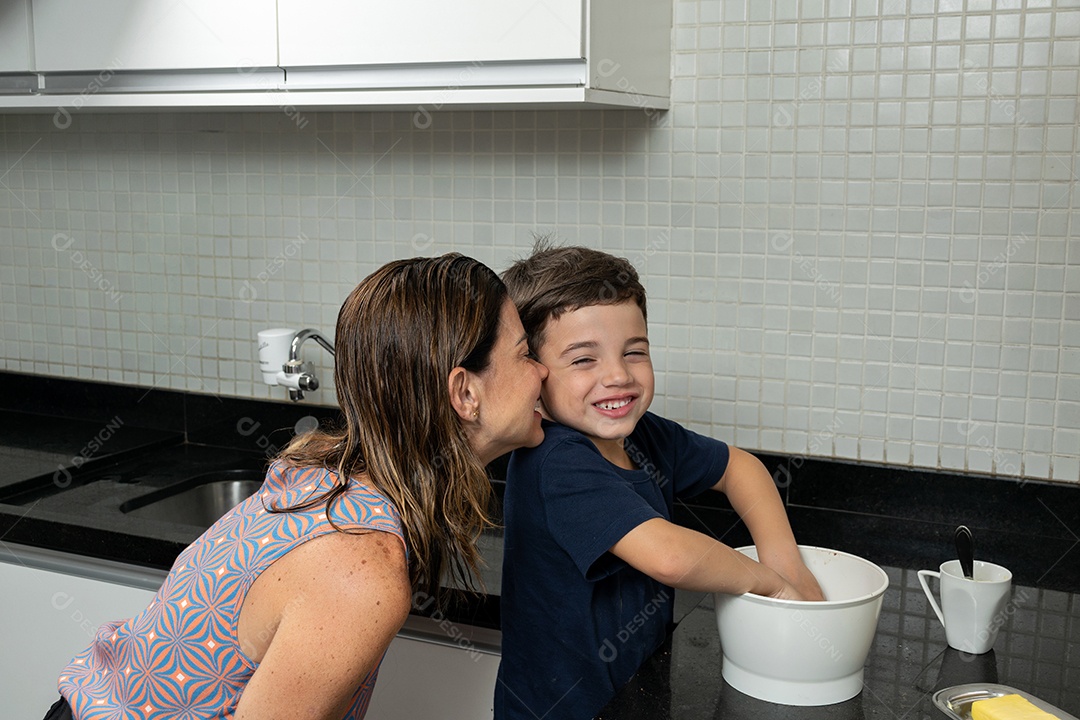 Mãe e filho fazendo biscoitos de Natal e interagindo em sua própria cozinha.