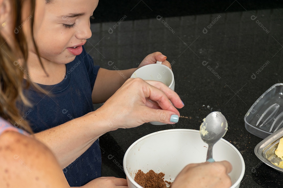 Garoto ajudando a mãe a fazer biscoitos e lambendo o dedo.
