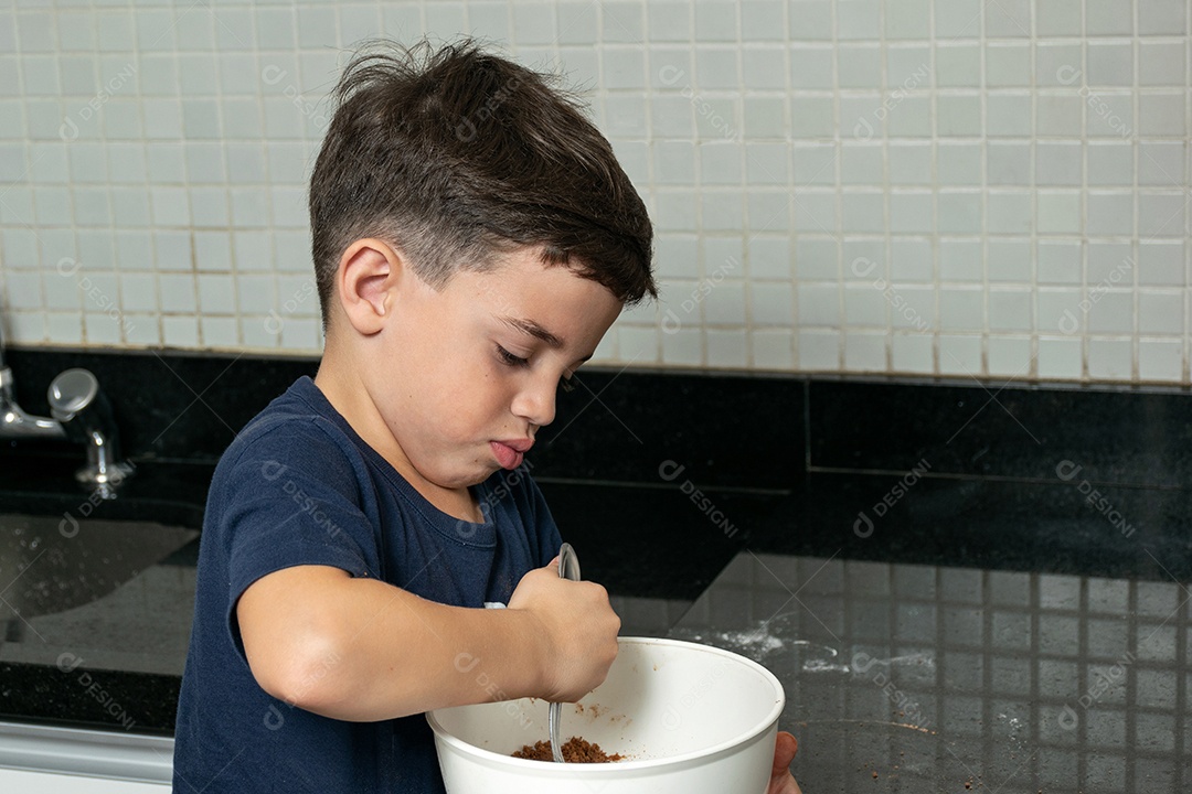 Garoto ajudando a mãe a fazer biscoitos e lambendo o dedo.