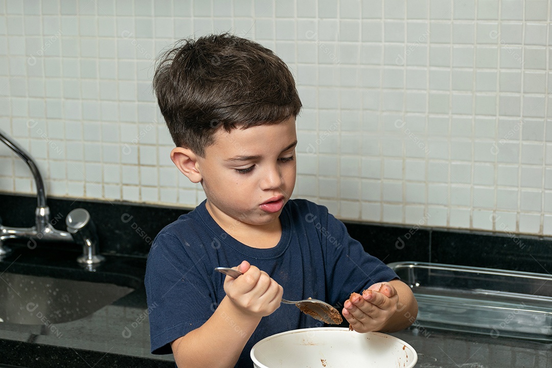 Garoto ajudando a mãe a fazer biscoitos e lambendo o dedo.