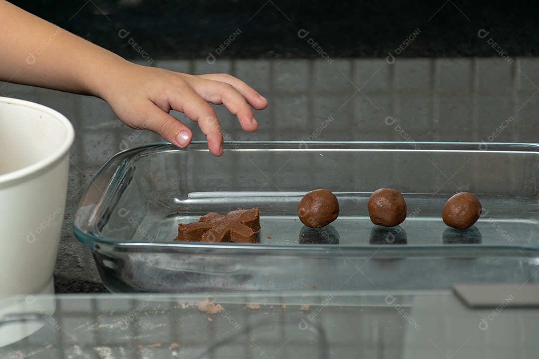 Garoto ajudando a mãe a fazer biscoitos e lambendo o dedo.