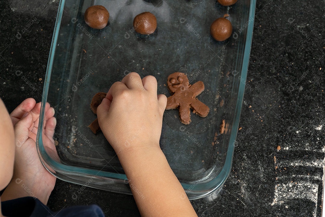 Garoto ajudando a mãe a fazer biscoitos e lambendo o dedo.