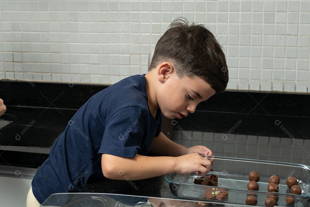 Garoto ajudando a mãe a fazer biscoitos e lambendo o dedo.