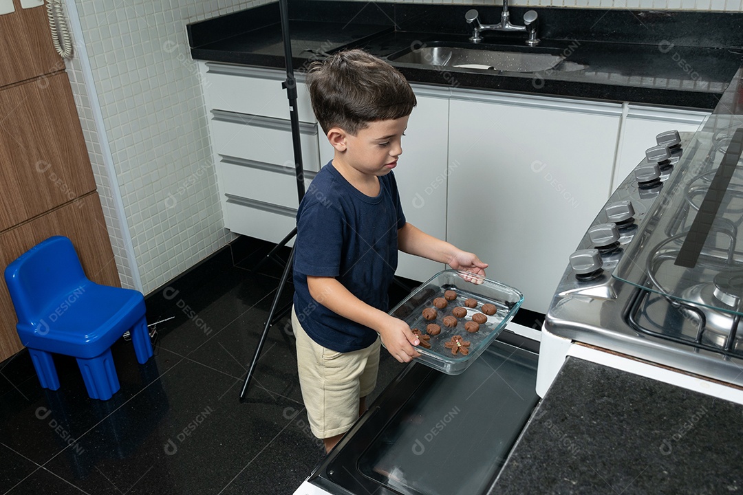 Garoto ajudando a mãe a fazer biscoitos e lambendo o dedo.