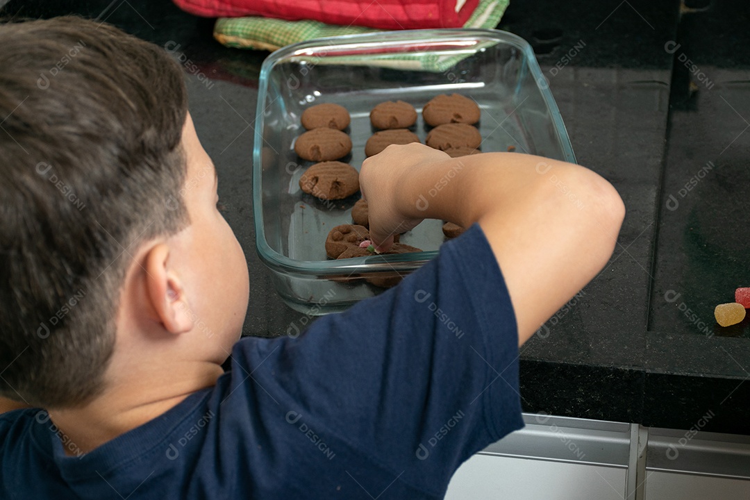 Menino terminando a decoração dos biscoitos.