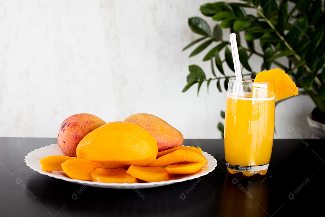 Prato de comida com pedaços manga fatiada copo de suco ao lado