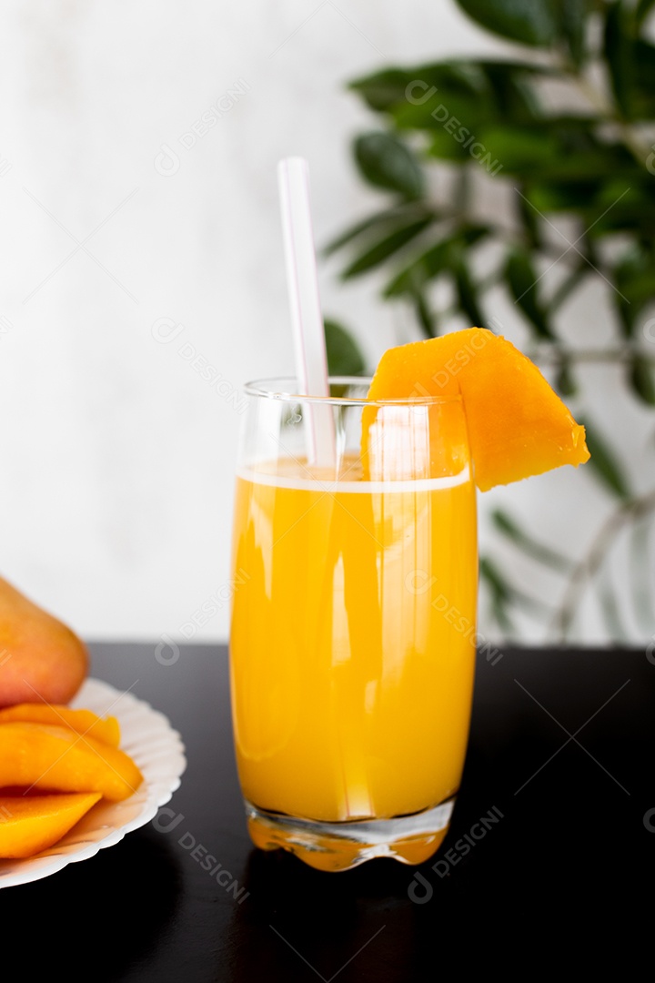 Prato de comida com pedaços manga fatiada copo de suco ao lado