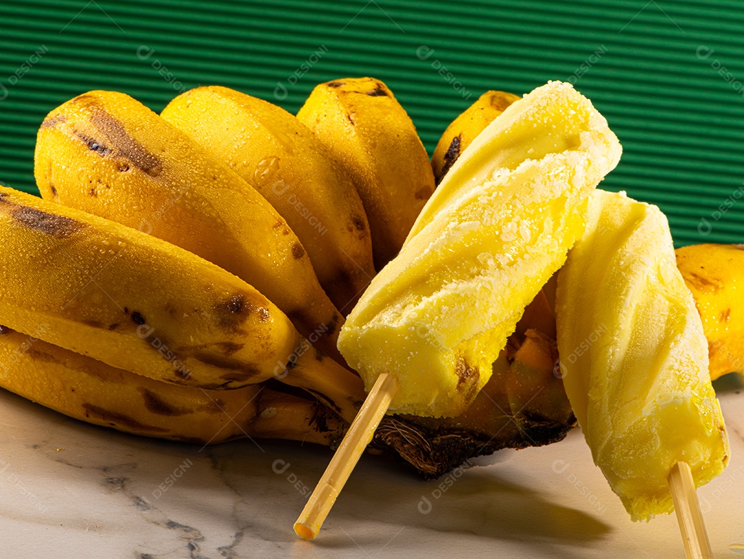 Sorvete de banana apoiado em cacho de banana em fundo branco.