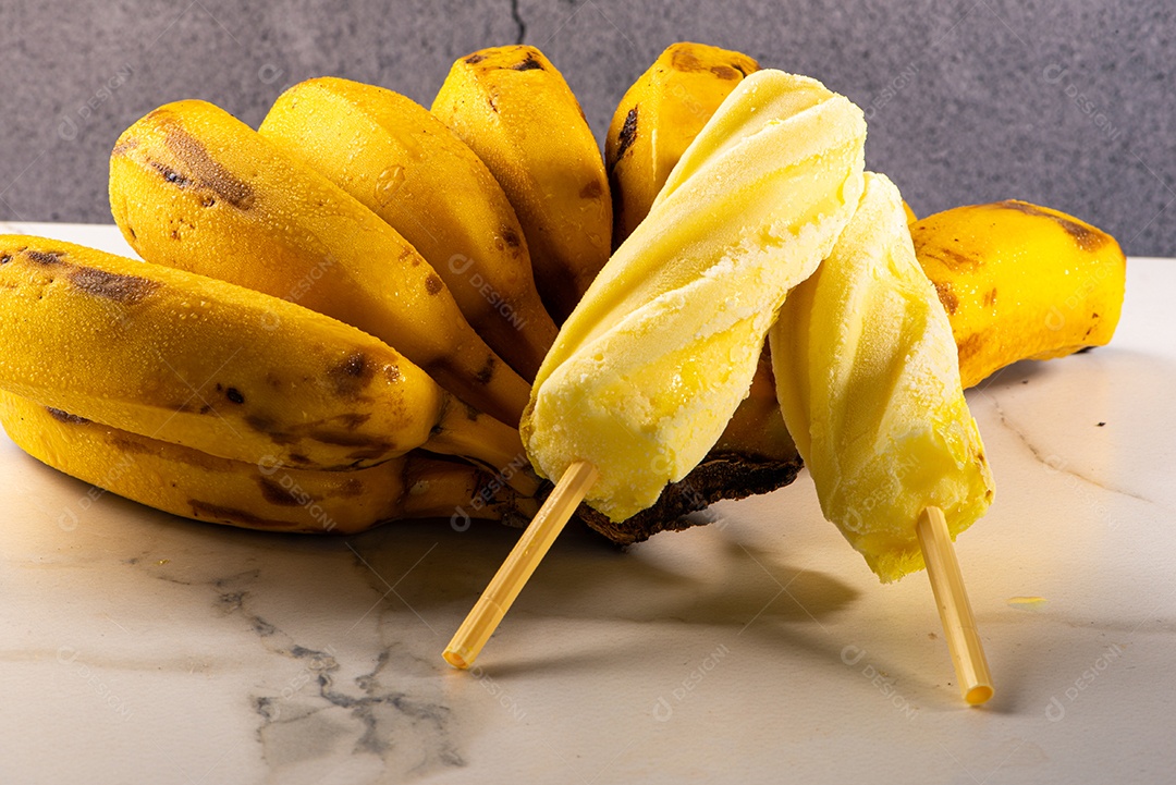 Sorvete de banana apoiado em cacho de banana em fundo branco.