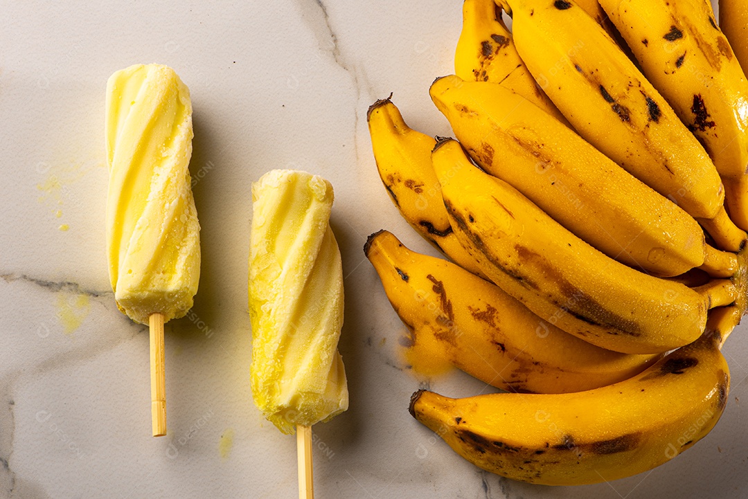 Sorvete de banana apoiado em cacho de banana em fundo branco.