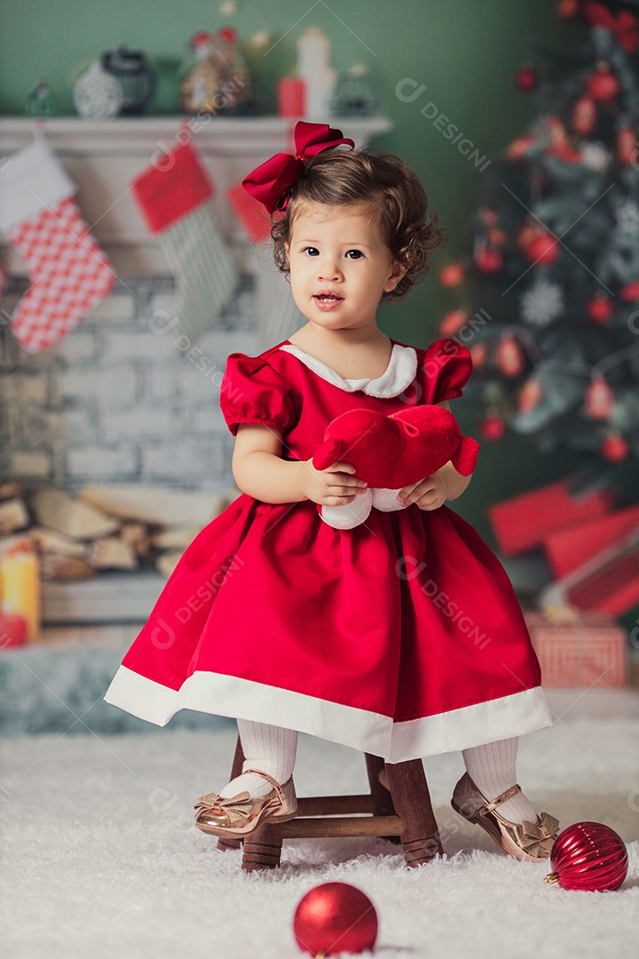 Linda menina fantasiada de Papai Noel sobre um linda casa decorada de Natal