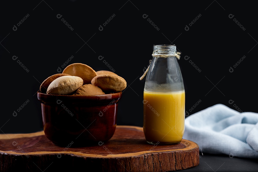 Biscoitos sobre uma tigela ao lado de jarra de suco tabua de madeira