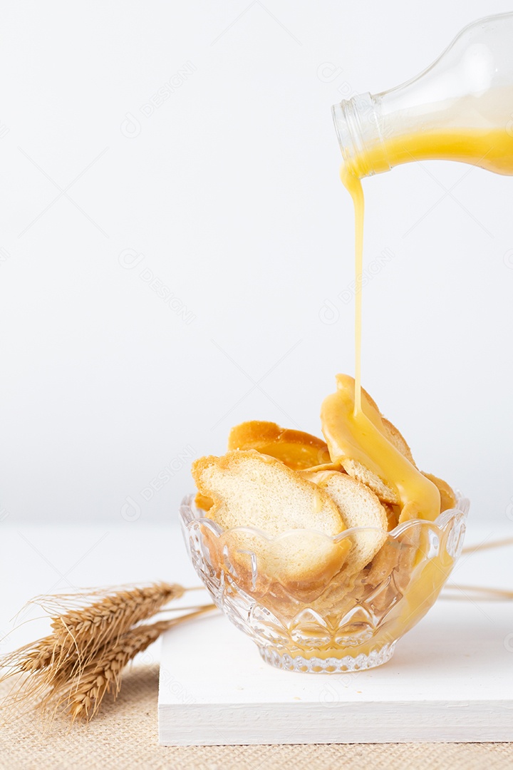 Pães sobre uma tigela ao lado de jarra de suco tabua de madeira