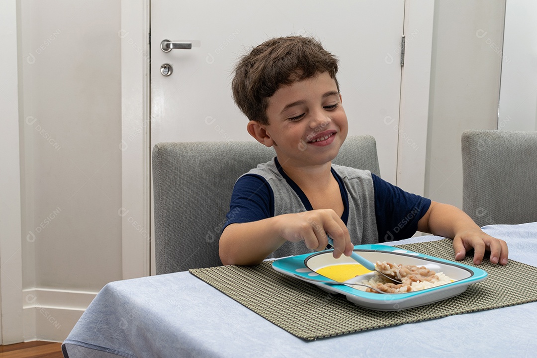 Criança de 6 anos jantando em casa hambúrguer caseiro, arroz branco e feijão