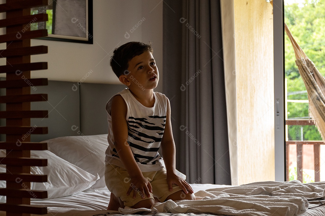 Criança relaxada assistindo TV no quarto do hotel com sua mãe deitada
