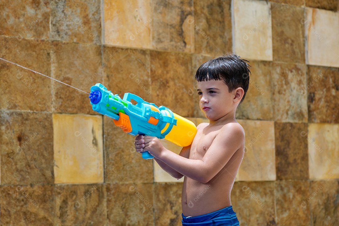 Menino garoto criança brincando segurando arma de agua sobre beira piscina