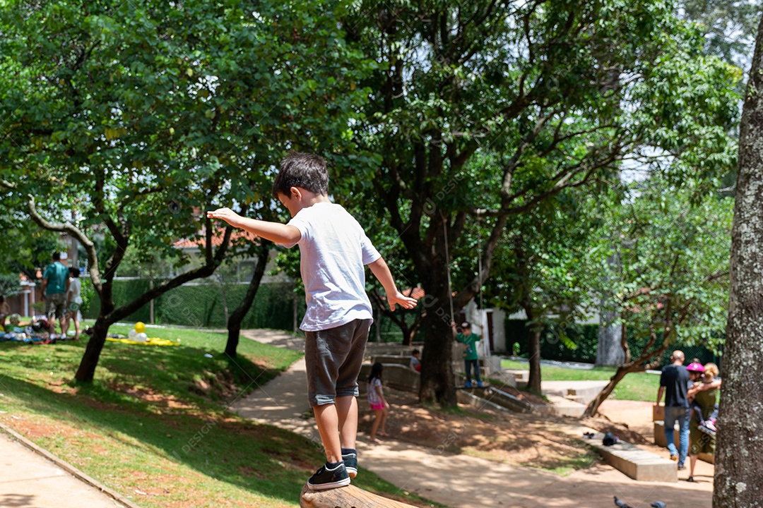 Criança de 6 anos andando de patinete e subindo no tronco de uma árvore na linda