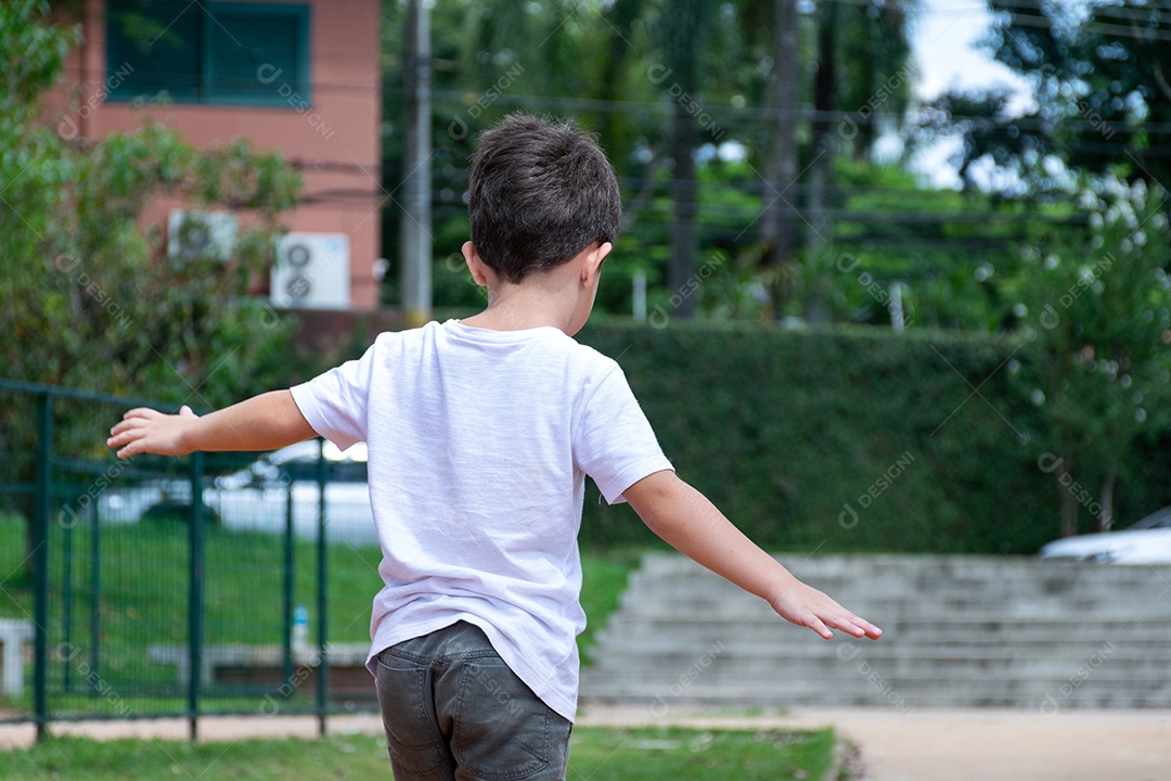 Criança de 6 anos andando de patinete e subindo no tronco de uma árvore na linda