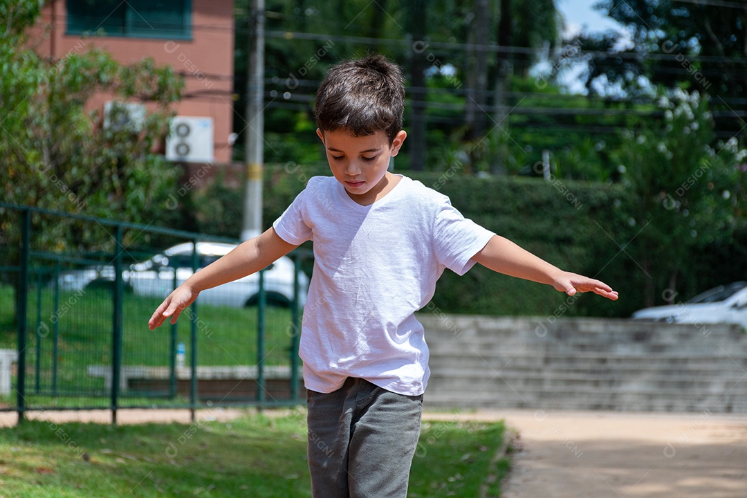 Criança de 6 anos andando de patinete e subindo no tronco de uma árvore na linda
