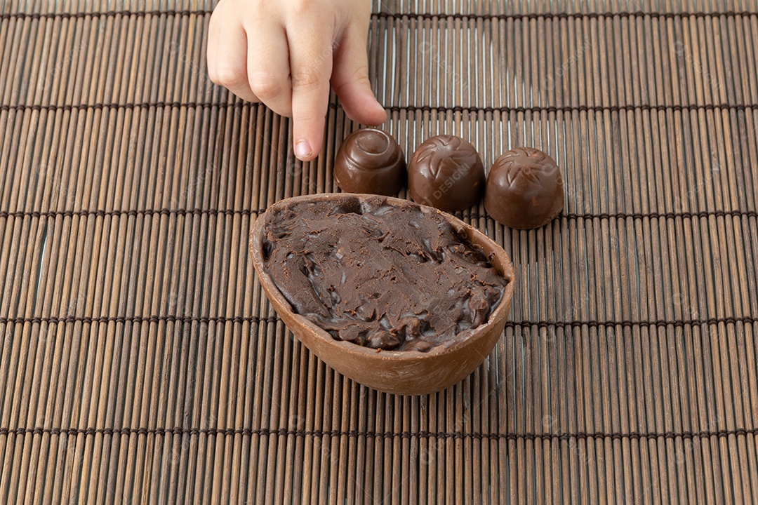 Mãos de uma criança pegando o ovo de Páscoa de chocolate