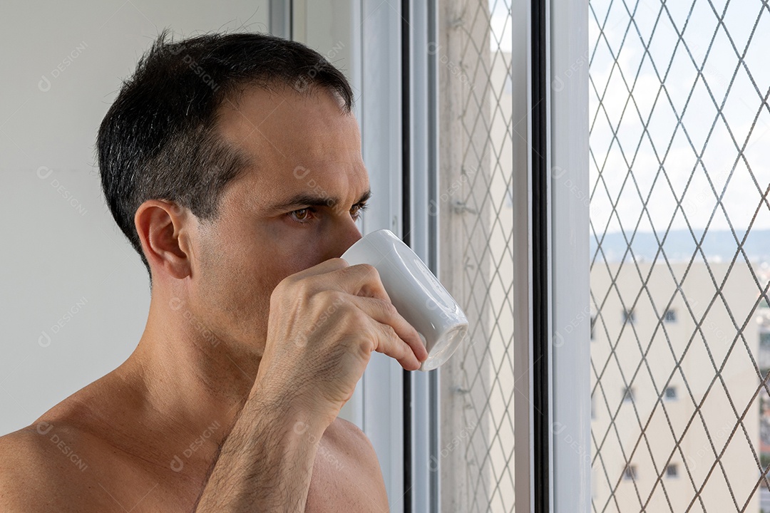 Homem de 44 anos bebendo uma xícara de café e olhando para o vento