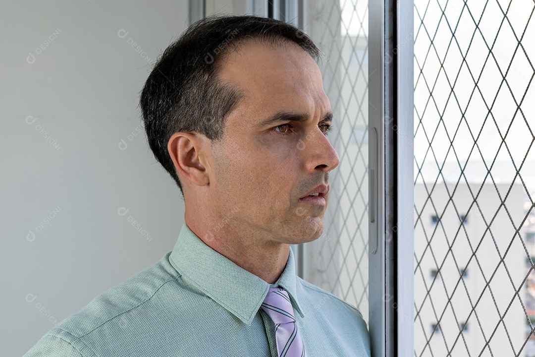 Homem de 44 anos em traje formal ao lado da janela