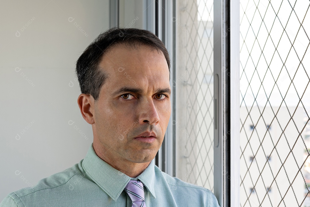 Homem de 44 anos em traje formal ao lado da janela