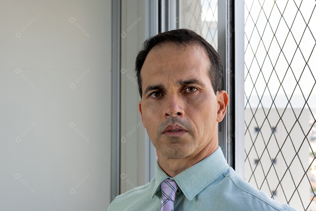 Homem de 44 anos em traje formal ao lado da janela