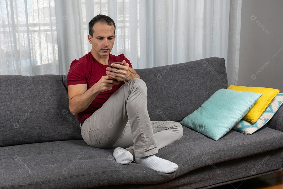 Homem jovem sentado sobre sofá sobre conforto de sua casa