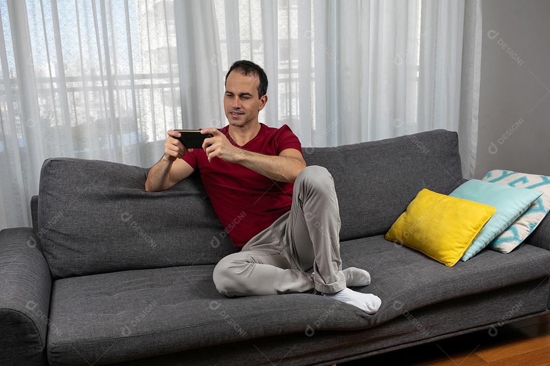 Homem jovem sentado sobre sofá sobre conforto de sua casa